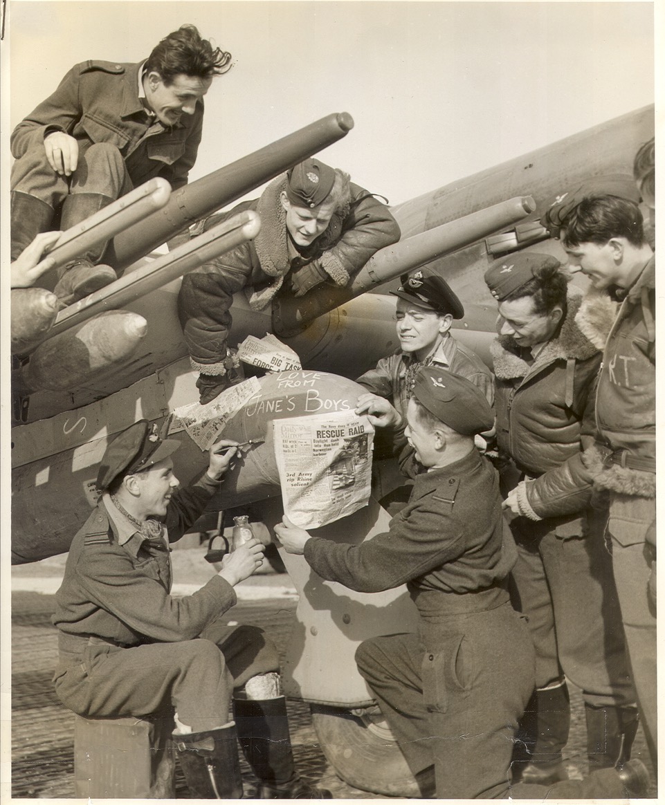 Lawrence sitting on the wing as his ground crew prepare his Typhoon with an extra special message for the Nazis.